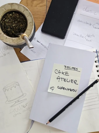 Cake Atelier Copenhagen recipe notebook with sketches, notes, pencil and mate on a worktable