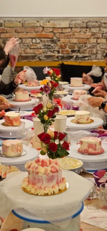 Cake decorating workshop table with participants working on small buttercream cakes